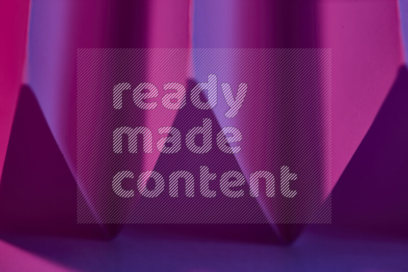 صورة مجردة مقربة تظهر طيات ورقية هندسية حادة بتدرجات اللون الارجواني