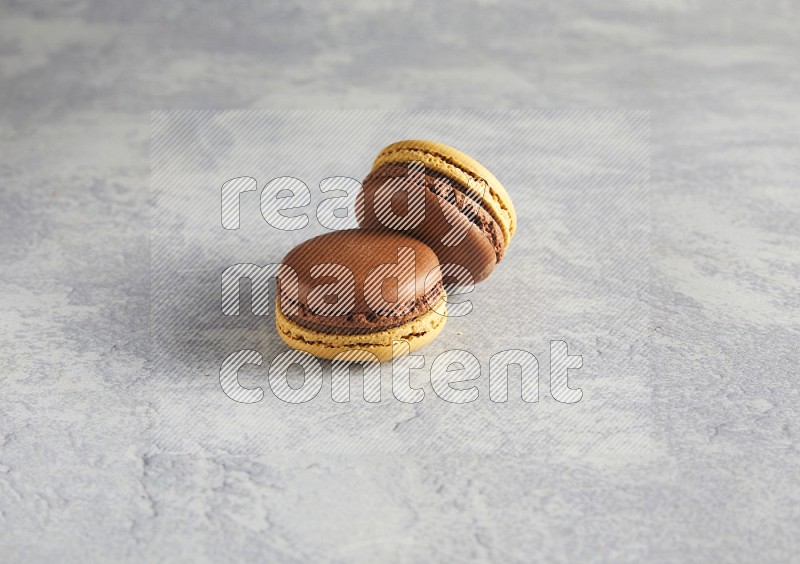 45º Shot of two Yellow and Brown Chai Latte macarons r on white  marble background