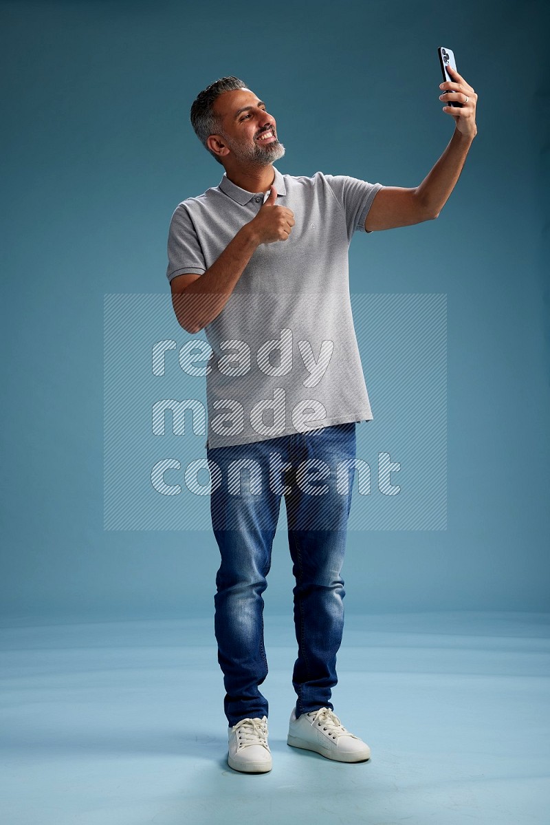 Man Standing taking selfie on blue background