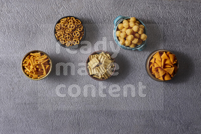 Assorted snacks in pottery bowls on grey background