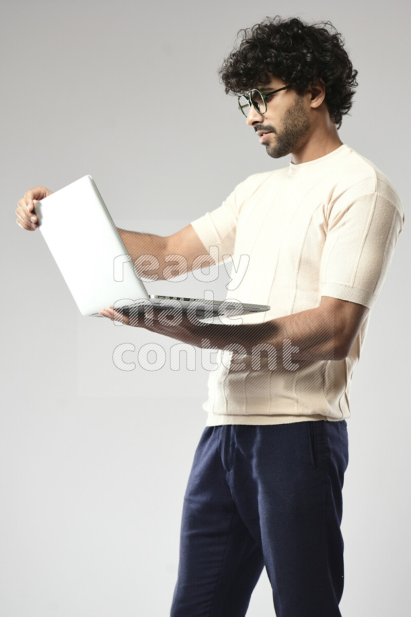 A man wearing casual standing and working on a laptop on white background