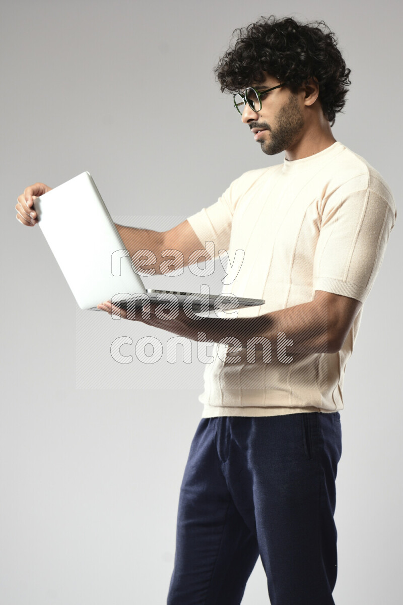 A man wearing casual standing and working on a laptop on white background
