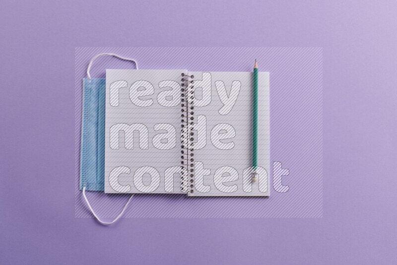 A blank open notebook with school supplies on purple background