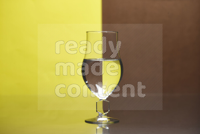 The image features a clear glassware filled with water, set against yellow and brown background