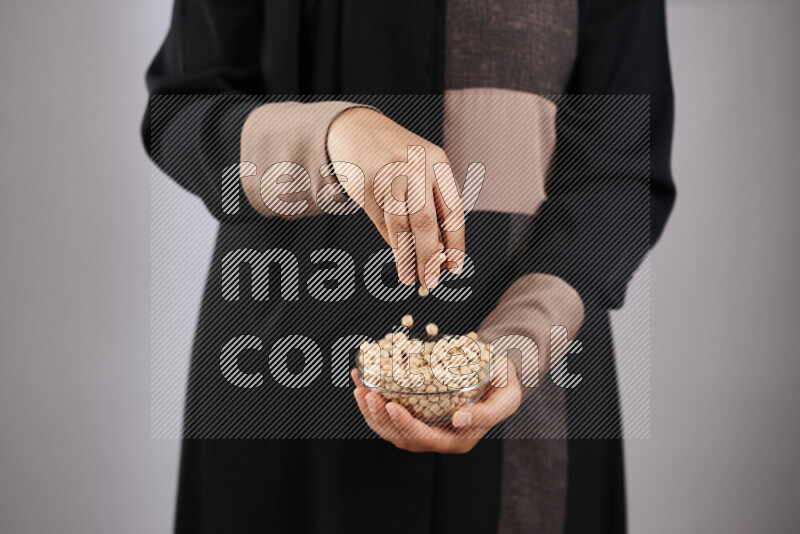 Woman in abaya holding different kinds of legumes in different positions