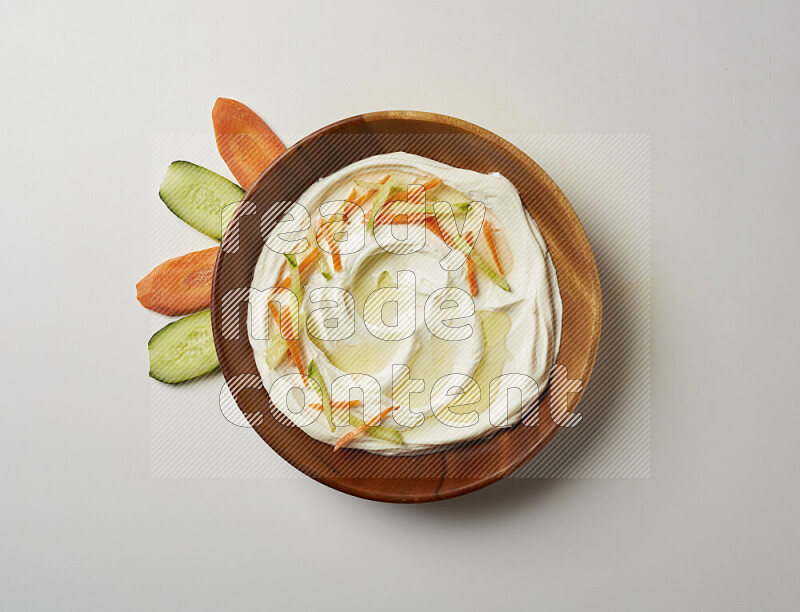Lebnah garnished with sliced carrots & cucumber in a wooden plate on a white background