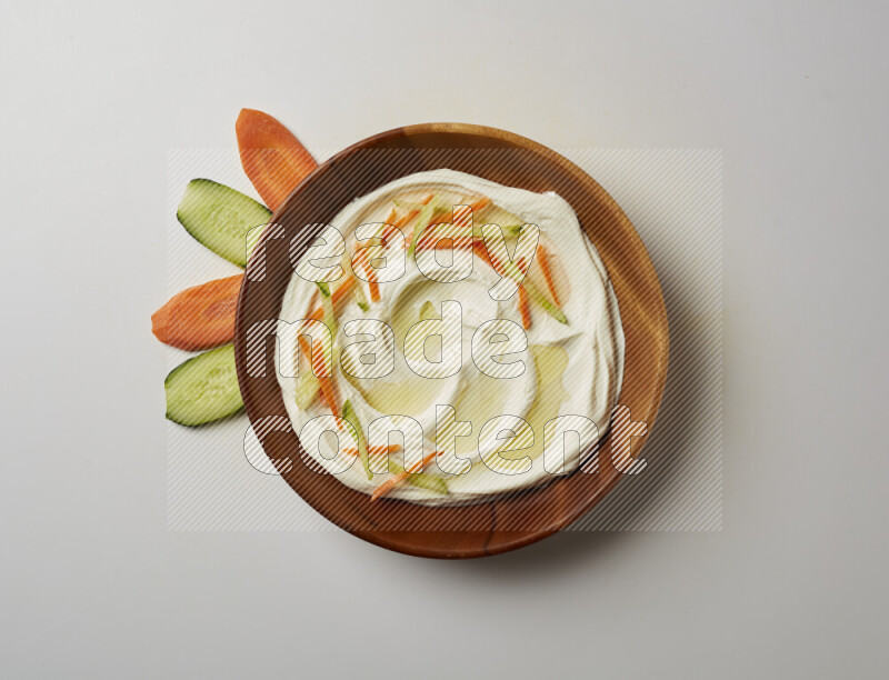 Lebnah garnished with sliced carrots & cucumber in a wooden plate on a white background