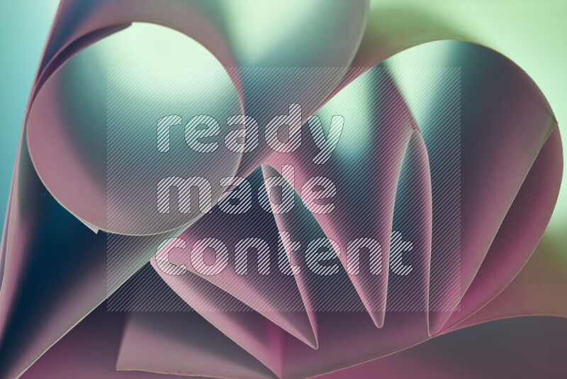 عرض فني لطيات الورق تخلق مزيج من الأشكال الهندسية، مضاءة بإضاءة ناعمة بدرجات اللون الأخضر والوردي