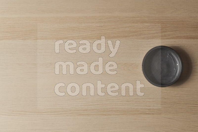 A black pottery bowl on light wooden background