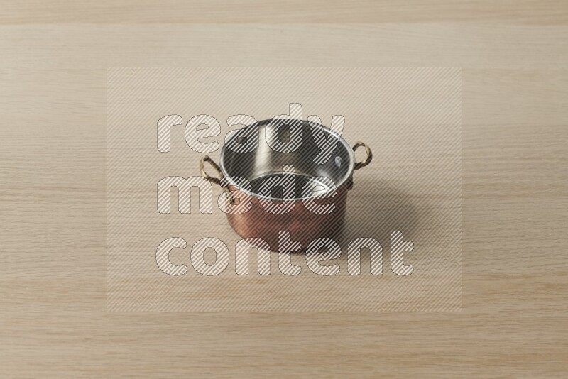 A small copper pot on light wooden background