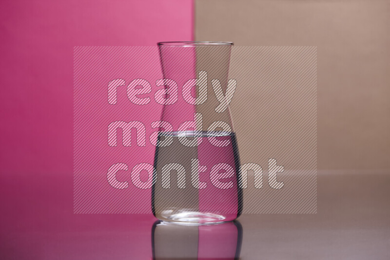 The image features a clear glassware filled with water, set against pink and beige background