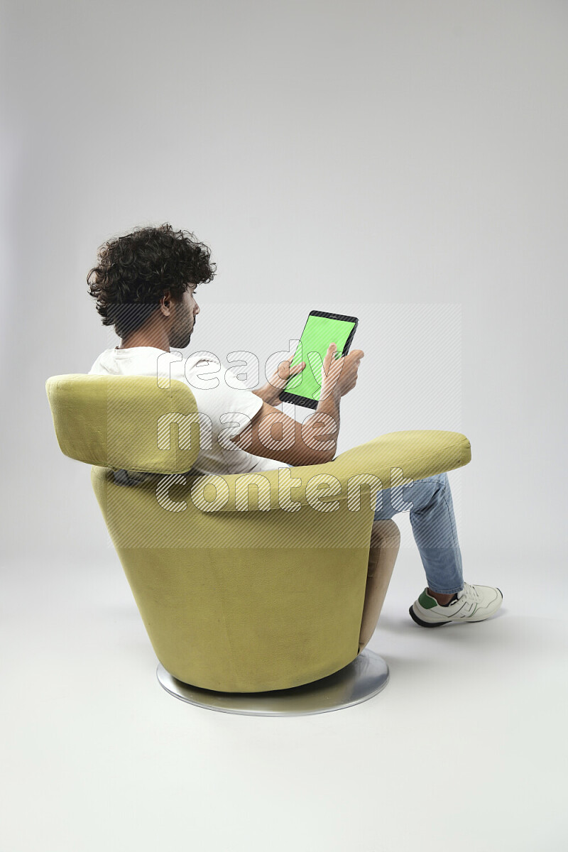 A man wearing casual sitting on a chair showing a tablet screen on white background