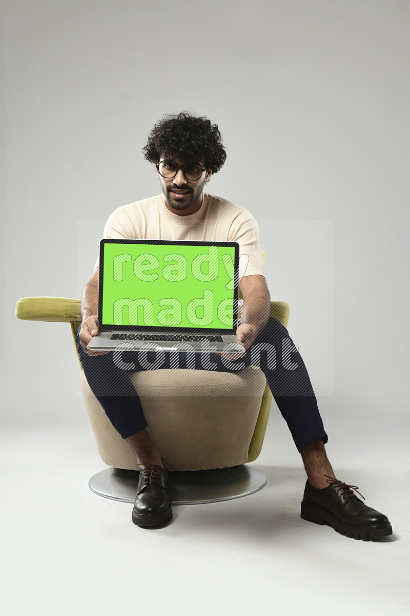 A man wearing casual sitting on a chair showing a laptop screen on white background