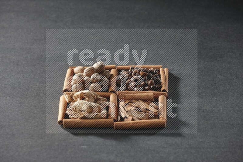 4 squares of cinnamon sticks full of coffee beans, cinnamon, dried ginger and nutmegs on black flooring