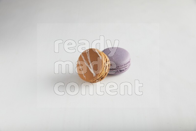 45º Shot of of two assorted Brown Irish Cream, and Purple Blueberry macarons on white background