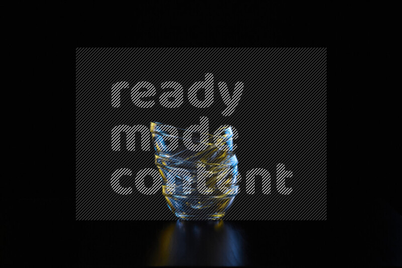 Glassware with rim light in blue and yellow against black background