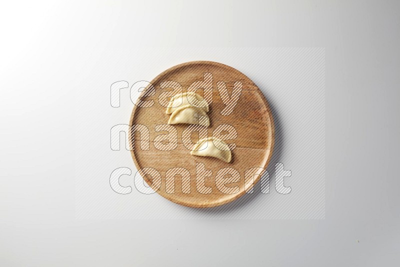 Three Sambosas on a wooden round plate on a white background