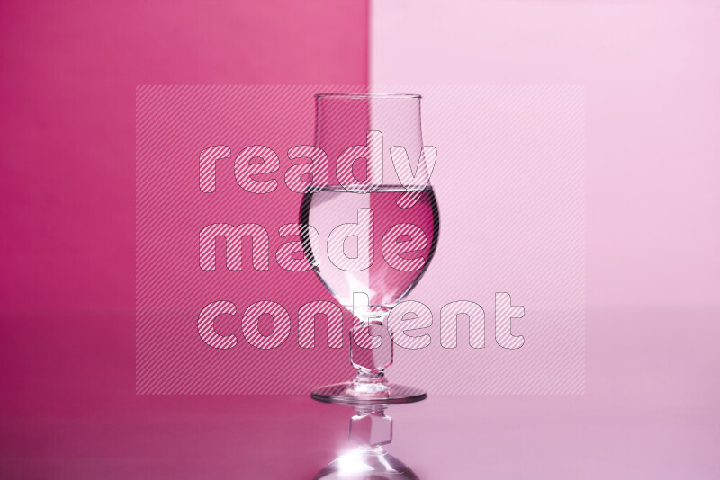 The image features a clear glassware filled with water, set against pink background