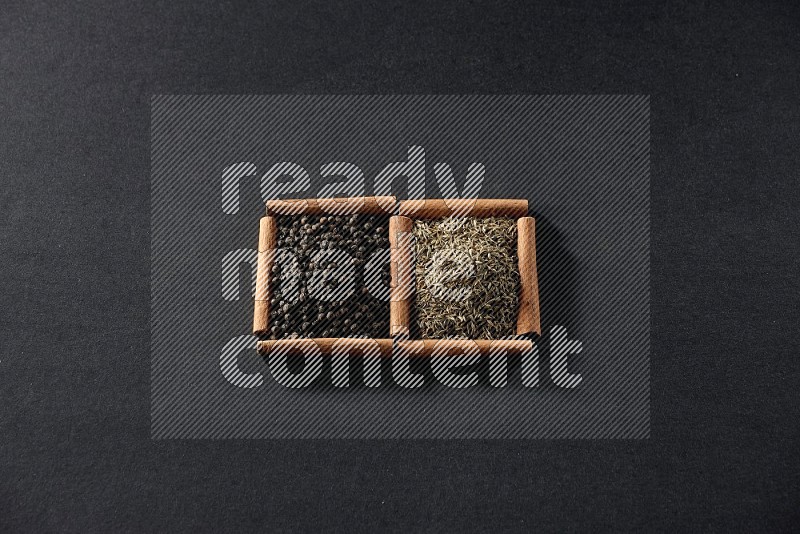 2 squares of cinnamon sticks full of black peppers and cumin on black flooring