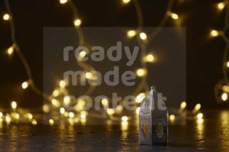 A traditional ramadan lantern surrounded by glowing fairy lights in a dark setup