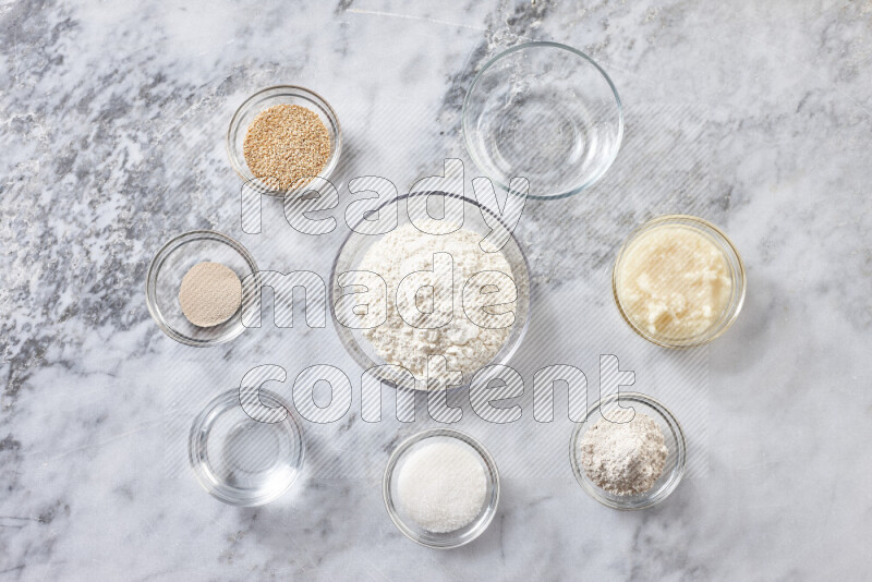 Kahk step by step with its ingredients ghee, sugar, flour, sesame, yeast, water and kahk flavor on grey marble background
