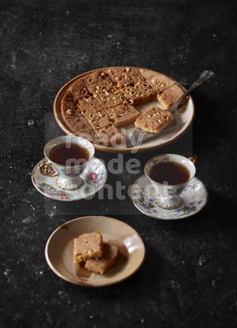 Basbousa with tea in a dark setup