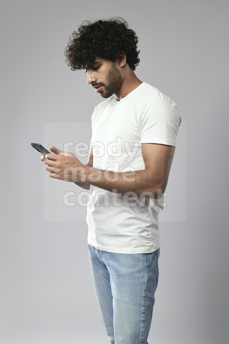 A man wearing casual standing and browsing on the phone on white background