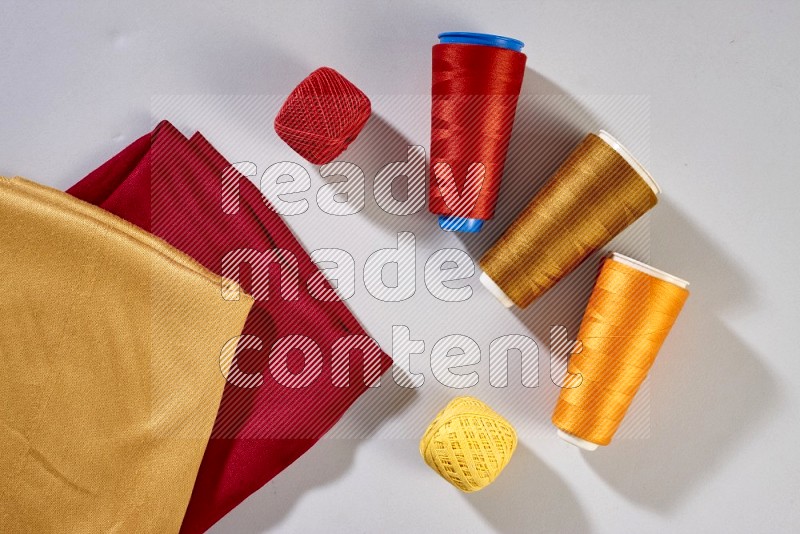 Multicolored fabrics with sewing supplies on grey background