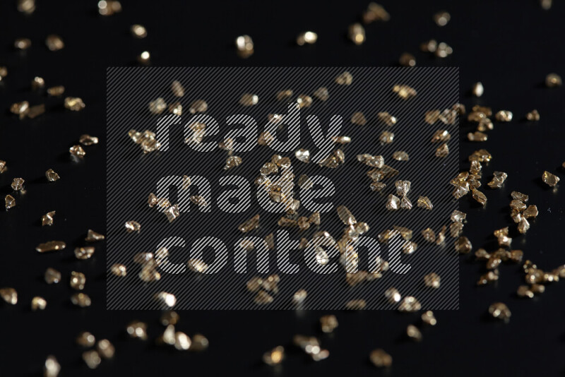 Gold shimmering fragments of glass scattered on a black background