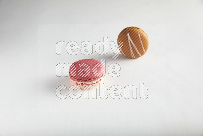 45º Shot of of two assorted Brown Irish Cream, and Pink Litchi Raspberry macarons on white background