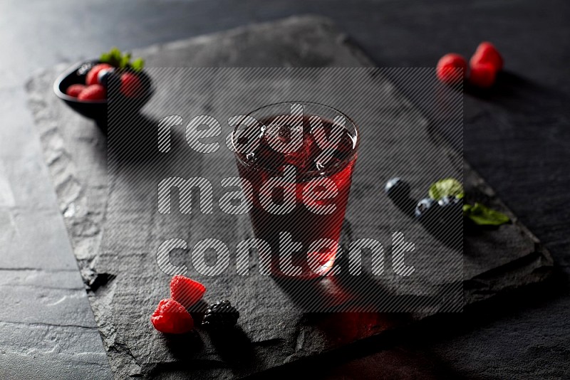 A glass of mixed berries juice on black background