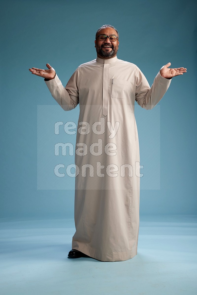 Saudi Man without shimag Standing Interacting with the camera on blue background