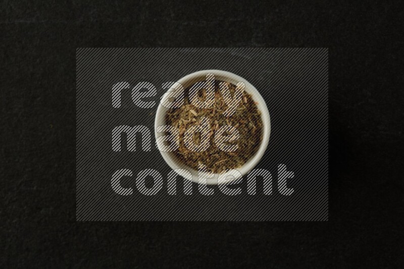 white ceramic round sauce bowl filled with herbs on grey textured countertop