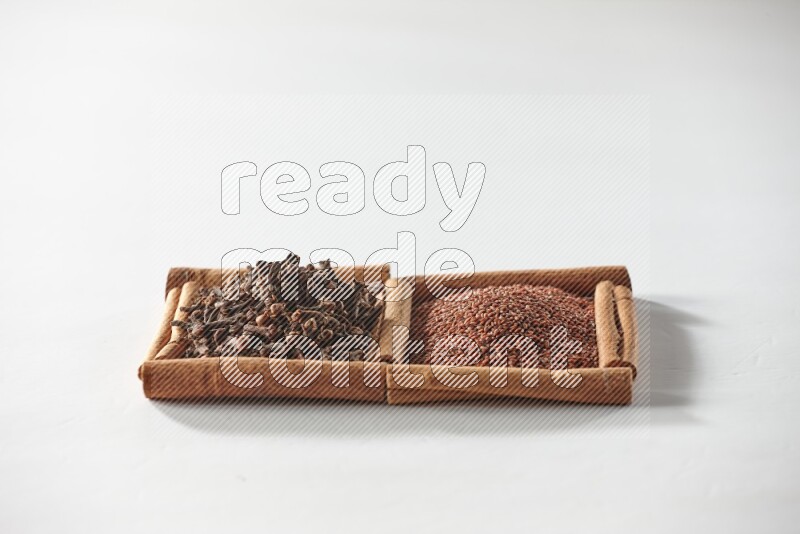 مربعان من أعواد القرفة ممتلئان بحب الرشاد والقرنفل علي خلفية بيضاء