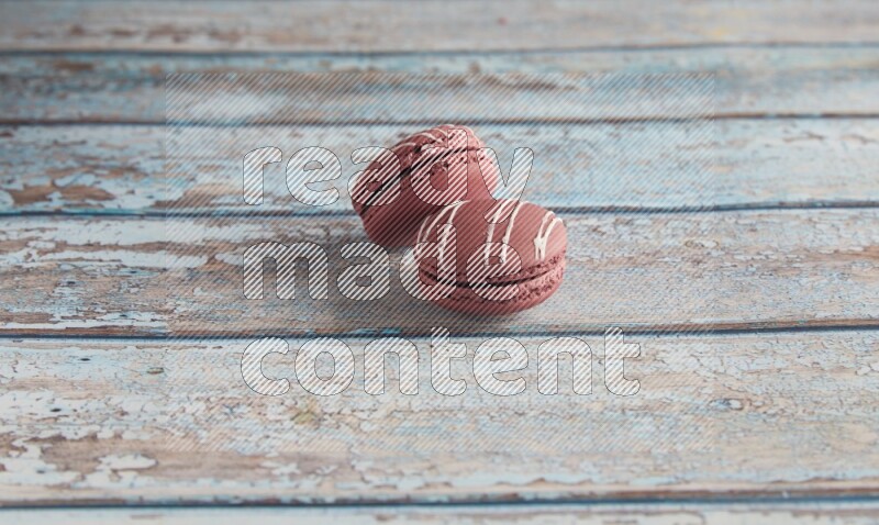 45º Shot of two Red Poppy Flower macarons on light blue wooden background