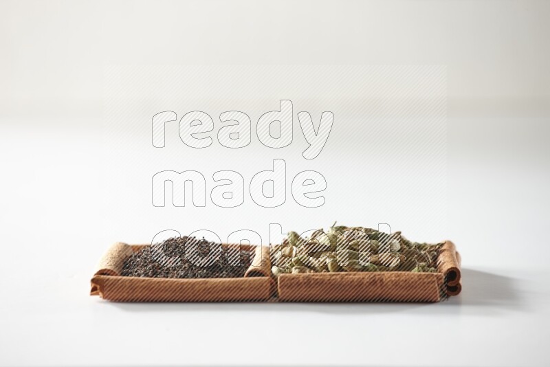 2 squares of cinnamon sticks full of cardamom and black tea on white flooring