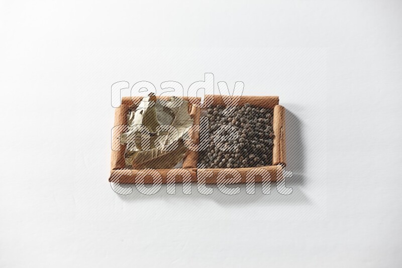 2 squares of cinnamon sticks full of black peppers and bay laurel leaves on white flooring