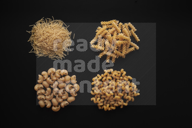 Different pasta types in bunches on black background
