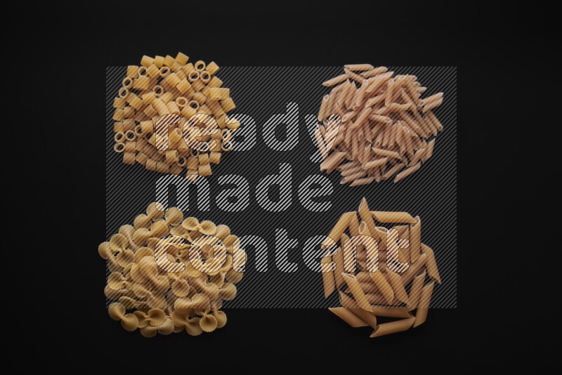 Different pasta types in bunches on black background