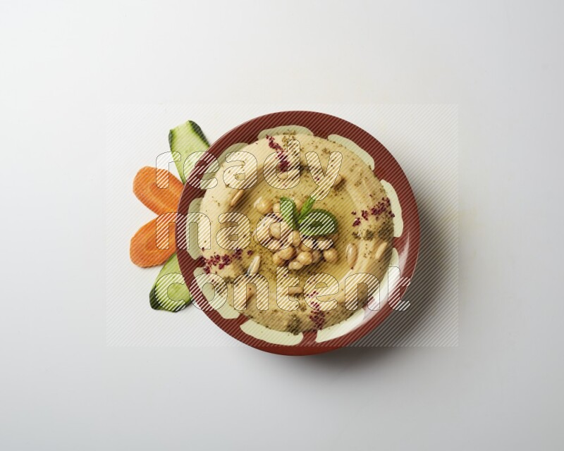 Hummus in a traditional plate garnished with zaatar & sumak on a white background