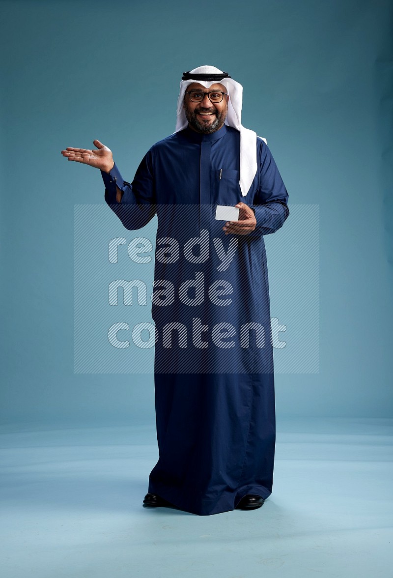 Saudi Man with shimag Standing holding ATM on blue background
