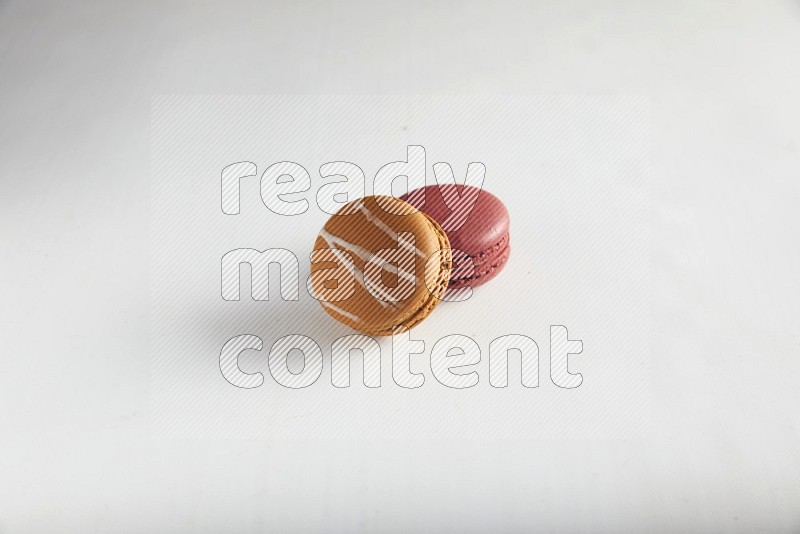 45º Shot of of two assorted Brown Irish Cream, and Red Velvet macarons on white background