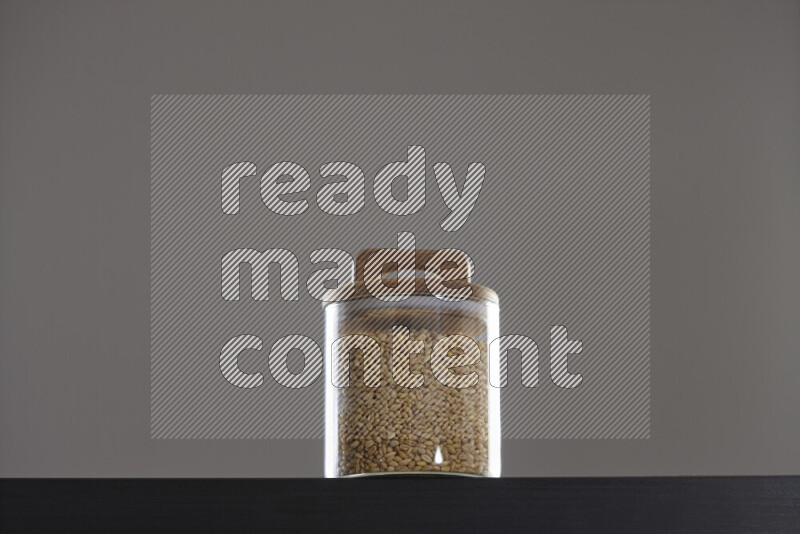Hulled wheat in a glass jar on black background