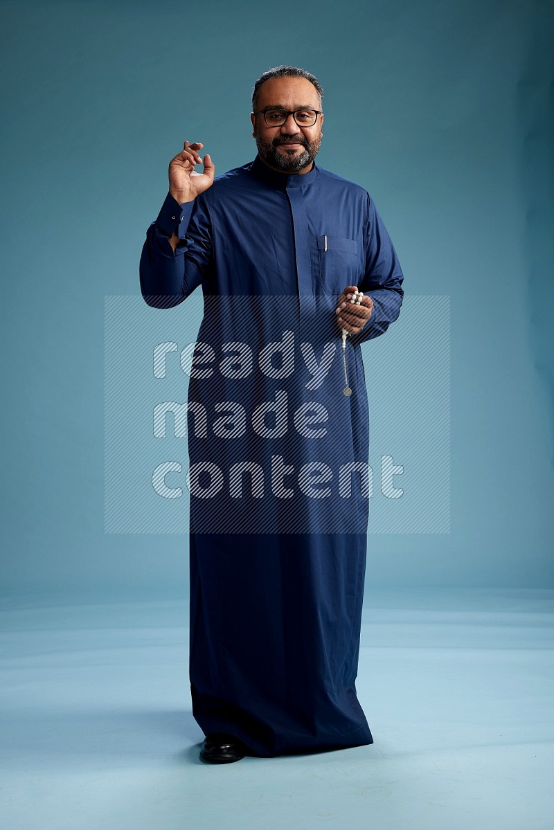 Saudi Man without shimag Standing Interacting with the camera on blue background