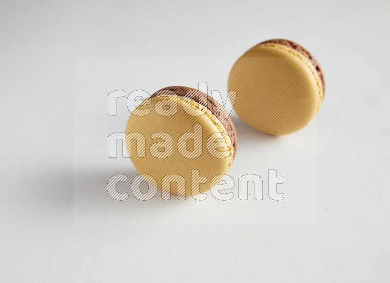 45º Shot of two Yellow and Brown Chai Latte macarons on white background