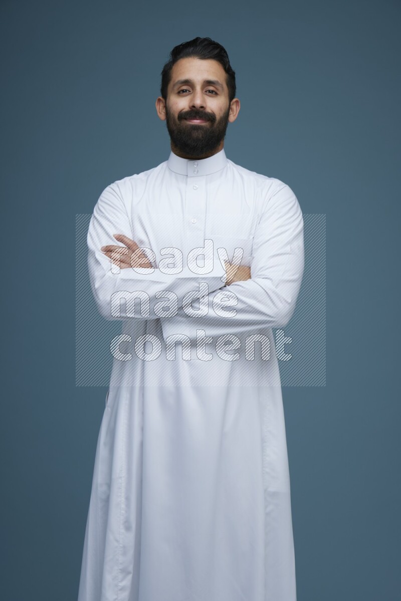 A man posing in a blue background wearing Saudi Thob