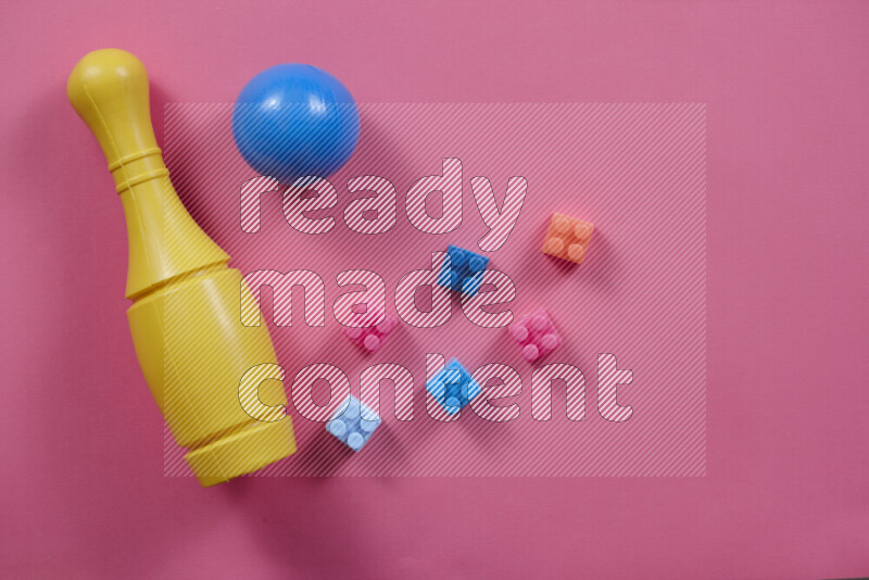 Plastic building blocks, balls and bowling pins on different colored backgrounds (kids toys)