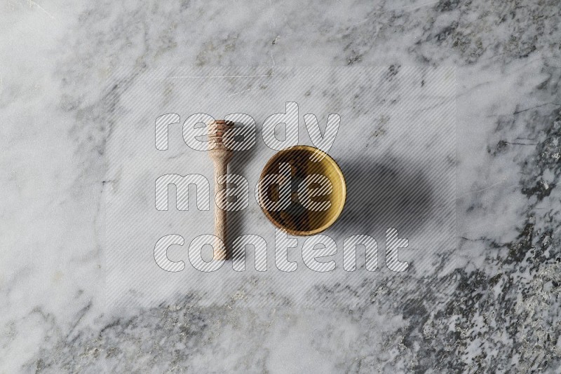 Multicolored Pottery Cup with wooden honey handle on the side on grey marble flooring, Top view