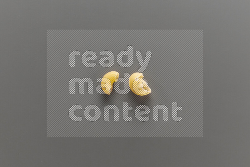 Elbow pasta with other types of pasta on grey background