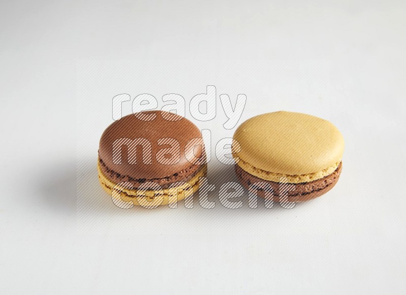 45º Shot of two Yellow and Brown Chai Latte macarons on white background